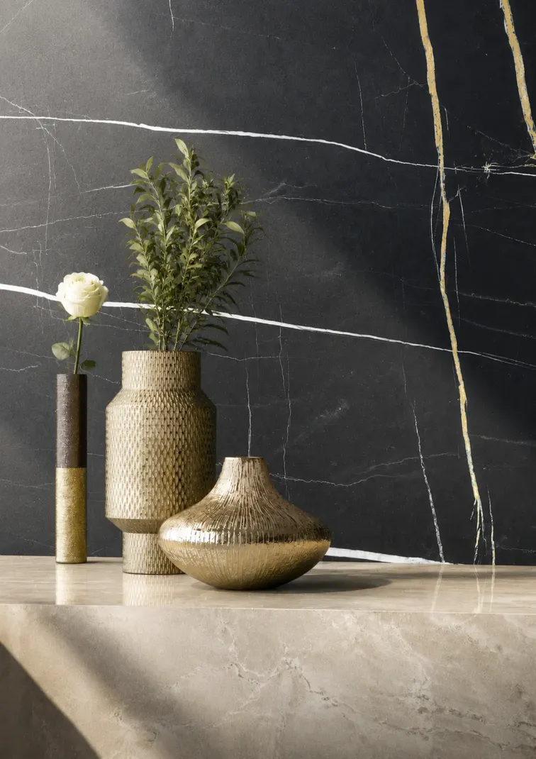 Vista frontale top effetto marmo beige oggetti d'orati riposti sopra e parete nera con particolari bianchi